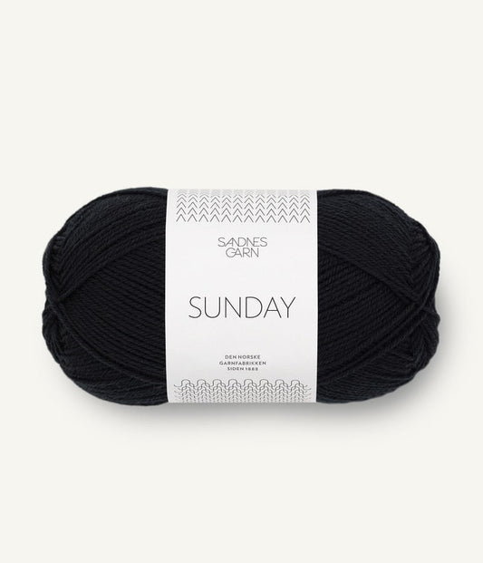 A ball of Sandnesgarn Sunday merino wool yarn in a black color, with packaging that includes the brand and product name.