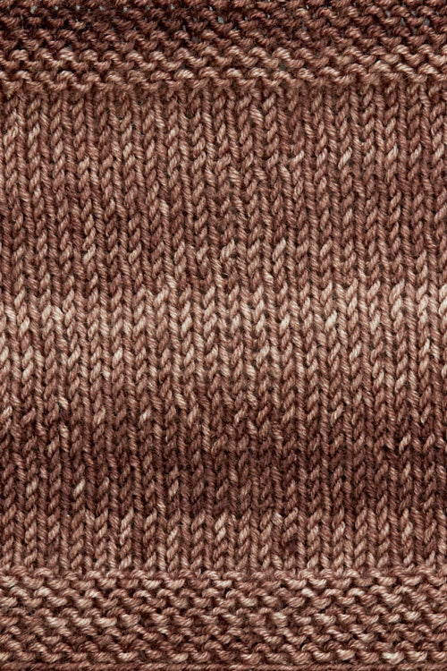 A knitted swatch of brown tonal superwash merino wool yarn from Urth