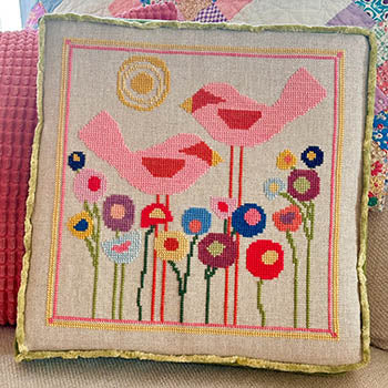 Decorative pillow with a cross stitch design of birds and flowers.