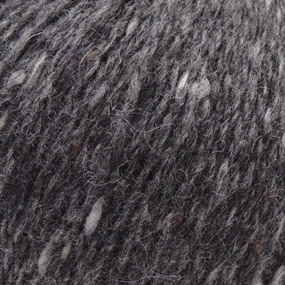 A close-up texture shot of a dark gray and black variegated yarn with lighter gray and white fibers mixed throughout.