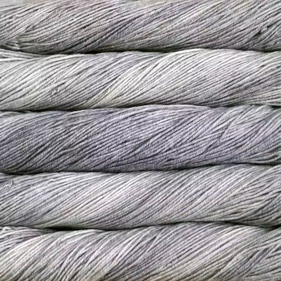 Close-up of tightly wound gray yarn or thread rolls stacked horizontally, filling the frame.