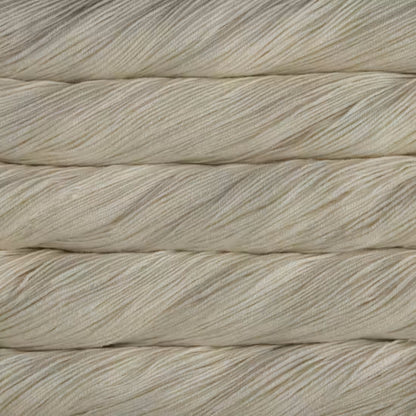 A close-up of cream-colored twisted yarn strands stacked horizontally, showing the texture and color of the fiber.
