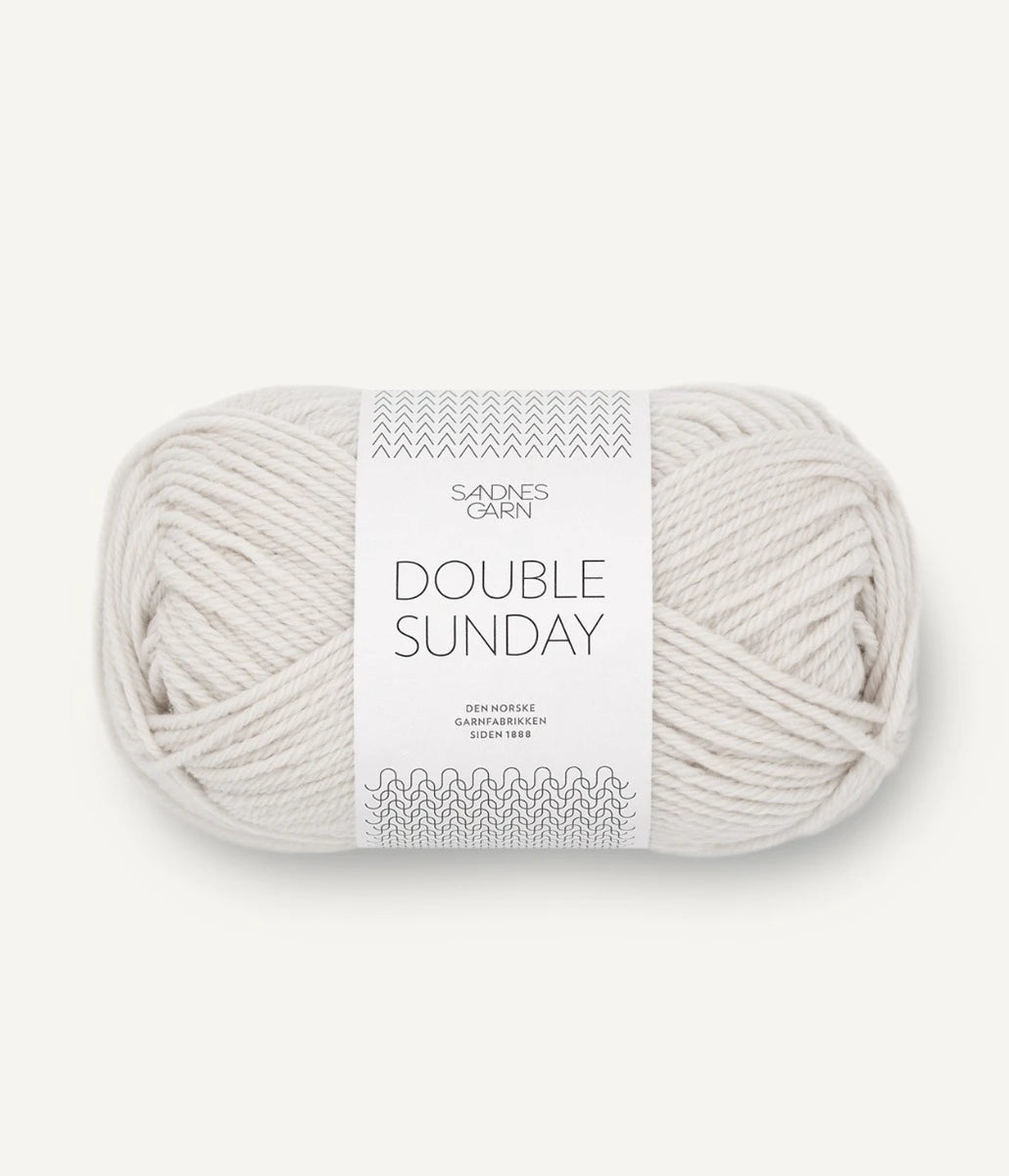 A ball of cream coloured merino wool yarn labeled 'Double Sunday' by Sandnesgarn.