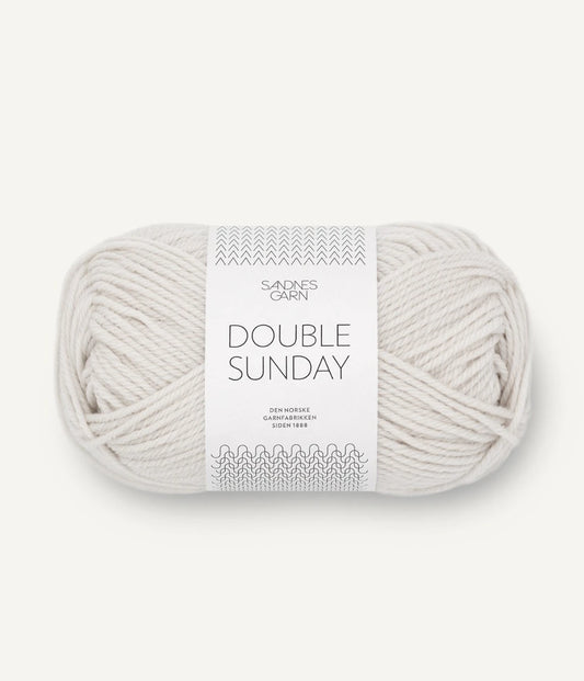 A ball of cream coloured merino wool yarn labeled 'Double Sunday' by Sandnesgarn.