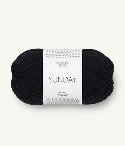 A ball of Sandnesgarn Sunday merino wool yarn in a black color, with packaging that includes the brand and product name.