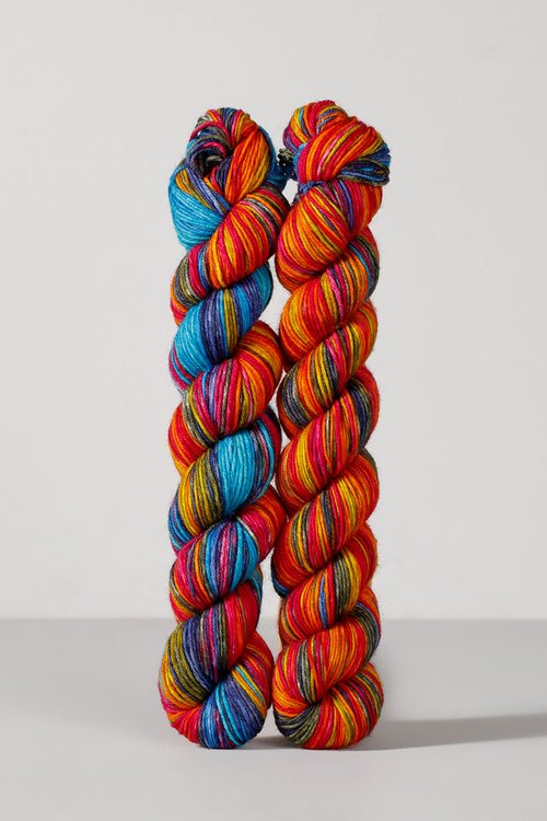 Two skeins of merino and nylon wool in rainbow tones from Urth Yarns in the Gusto line