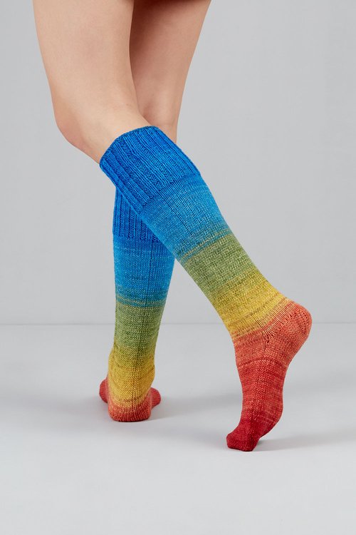 Knitted socks in orange, green, yellow, and blue tones from Urth Yarns in the Gusto line