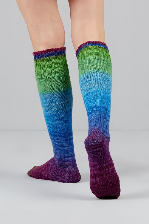 Knitted socks in blue, green, and purple tones from Urth Yarns in the Gusto line