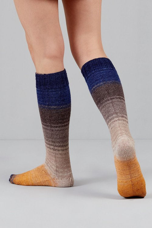 Knitted socks in indigo, grey, and yellow tones from Urth Yarns in the Gusto line