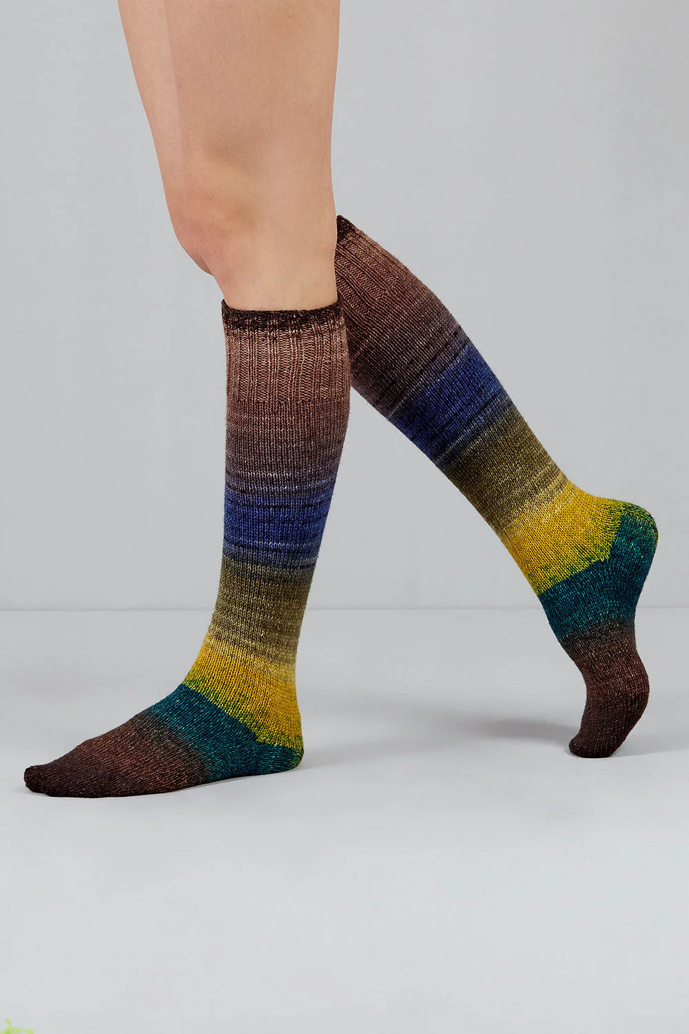 Knitted socks in brown, teal, yellow, and purple tones from Urth Yarns in the Gusto line