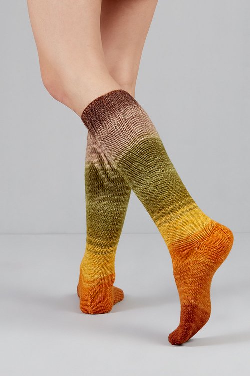 Knitted socks in orange, yellow, green, and brown tones from Urth Yarns in the Gusto line