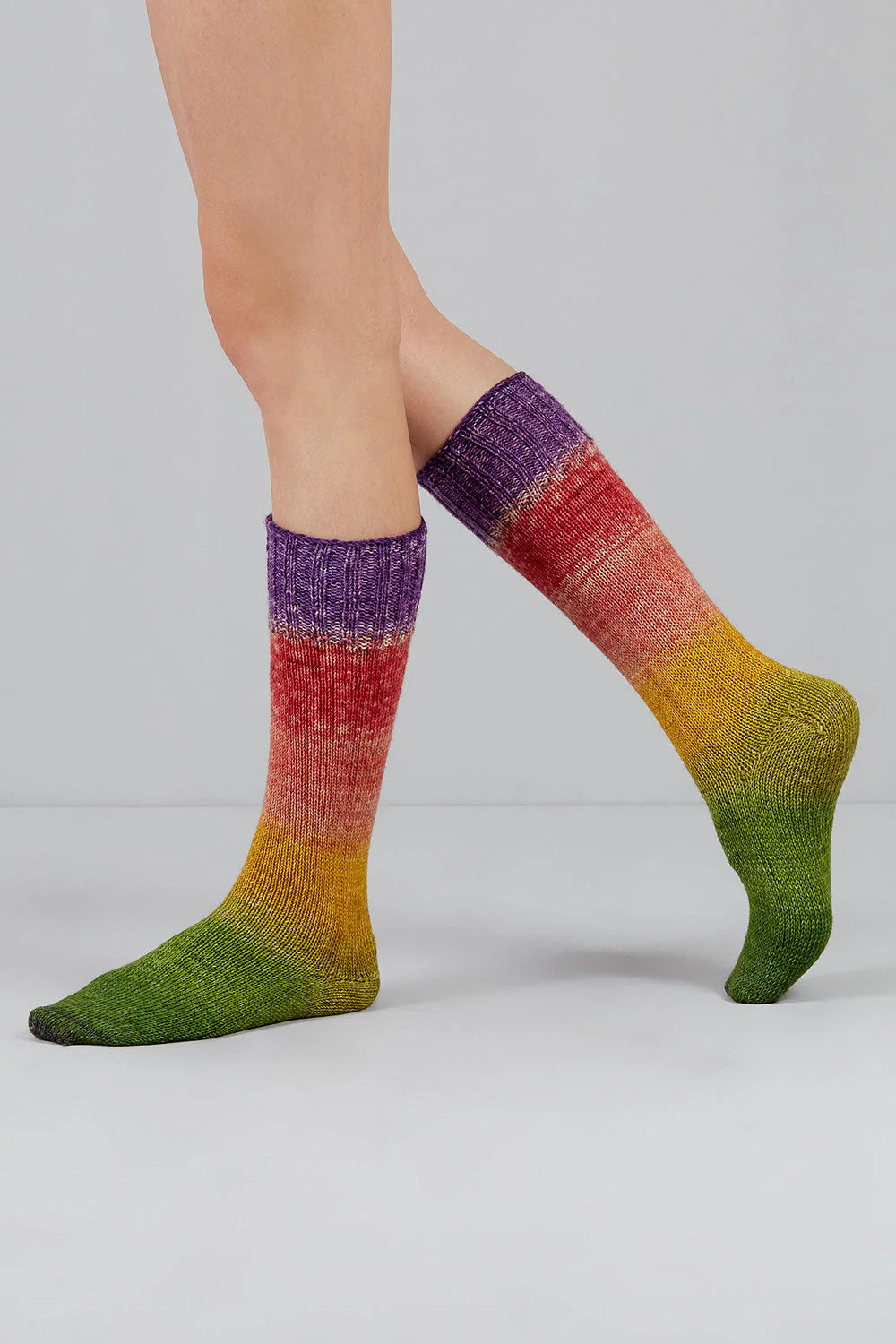Knitted socks in green, yellow, pink, and purple tones from Urth Yarns in the Gusto line