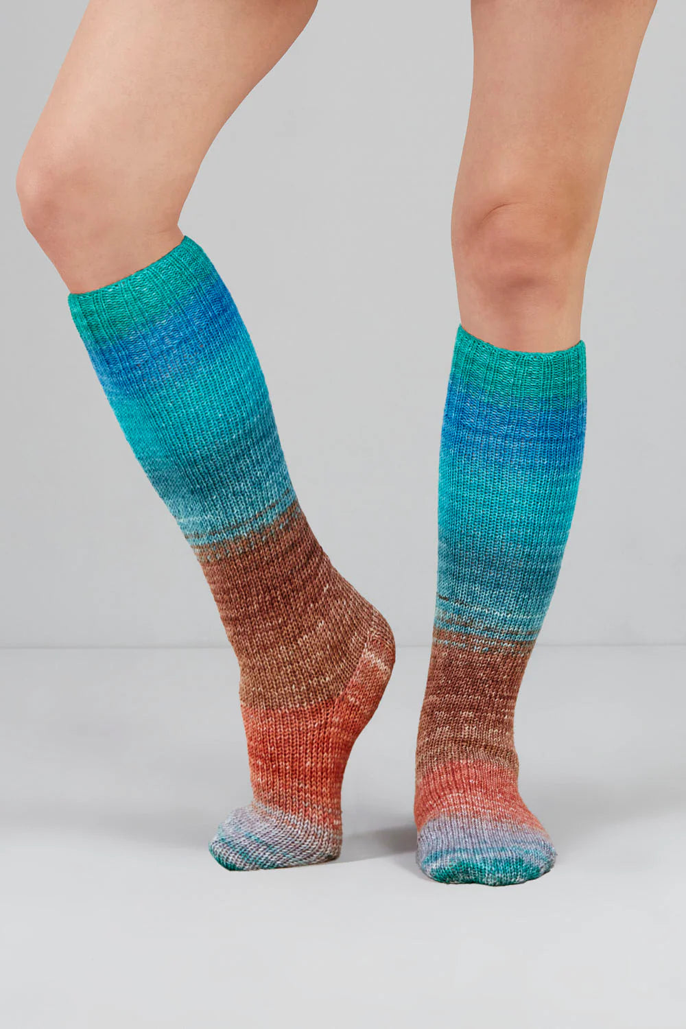 Knitted socks in teal and rust tones from Urth Yarns in the Gusto line