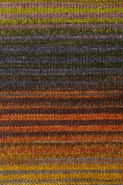 a knitted swatch of merino yarn with orange, grey, and yellow tones from Urth yarns