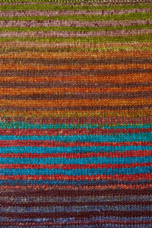 a knitted swatch of merino yarn with orange, blue, green, red, and brown tones from Urth yarns