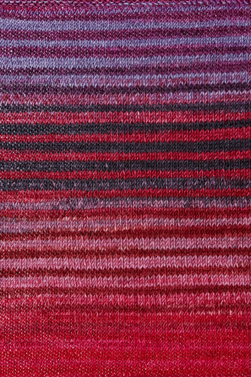 a knitted swatch of merino yarn with pink and red tones from Urth yarns