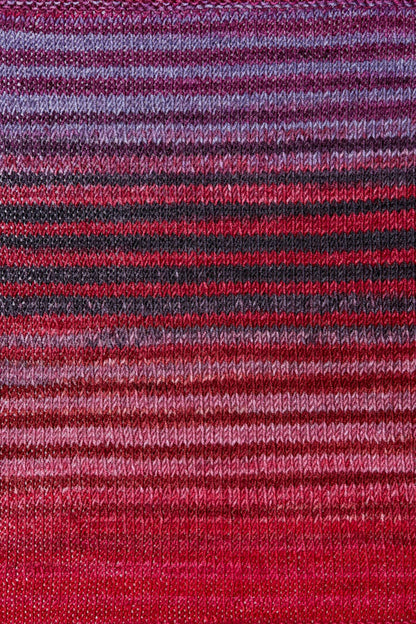 a knitted swatch of merino yarn with pink and red tones from Urth yarns