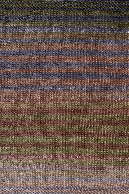 a knitted swatch of merino yarn with grey, brown, and khaki tones from Urth yarns