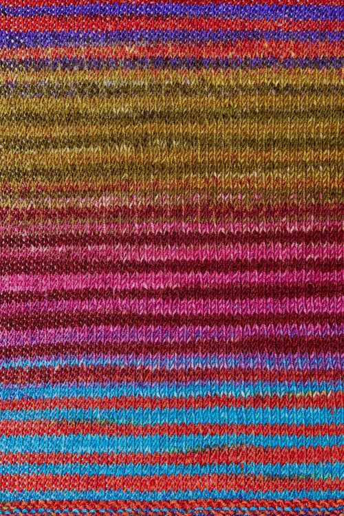 a knitted swatch of merino yarn with blue, pink, purple, and green/yellow tones from Urth yarns