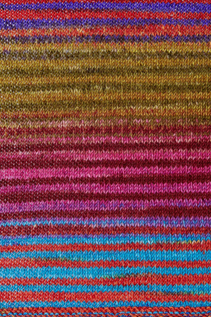 a knitted swatch of merino yarn with blue, pink, purple, and green/yellow tones from Urth yarns
