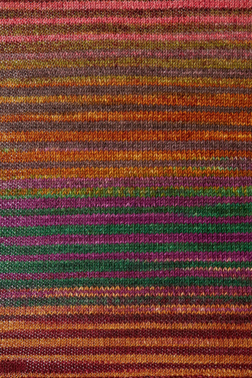 a knitted swatch of merino yarn with orange, green, and purple tones from Urth yarns
