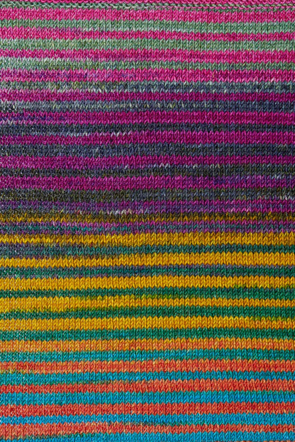 a knitted swatch of merino yarn with pink, yellow, grey, orange, and teal tones from Urth yarns