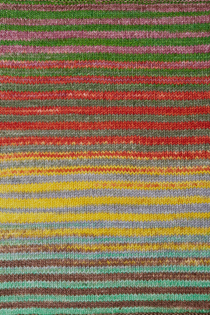 a knitted swatch of merino yarn with yellow, green, red, grey, and teel tones from Urth yarns