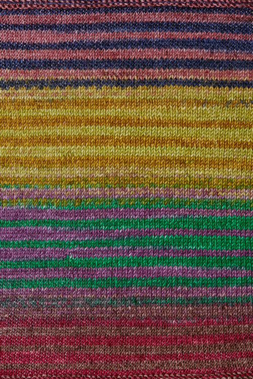 a knitted swatch of merino yarn with yellow, purple, green, and red tones from Urth yarns