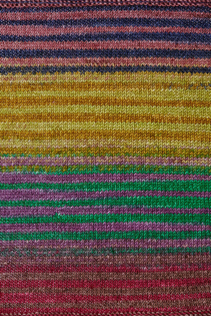 a knitted swatch of merino yarn with yellow, purple, green, and red tones from Urth yarns