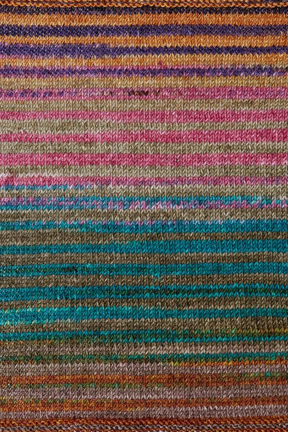 a knitted swatch of merino yarn with purple, orange, pink and teal tones from Urth yarns