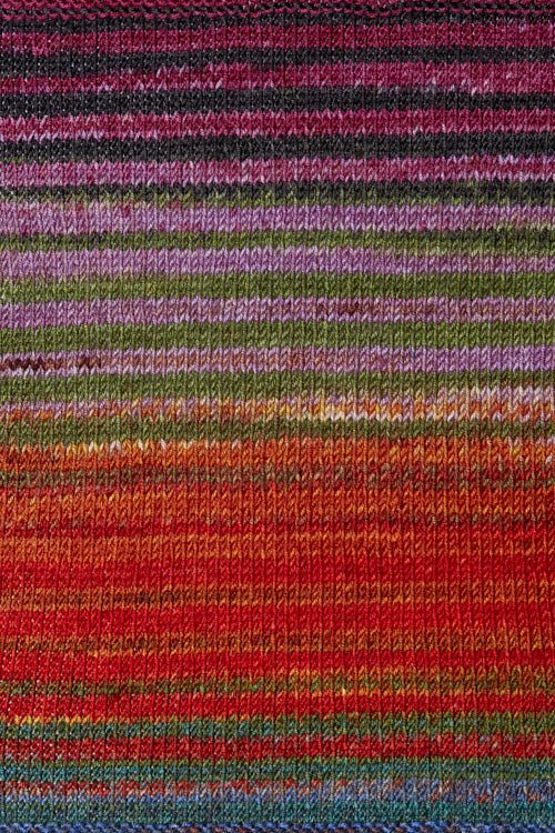 a knitted swatch of merino yarn with orange, green, pink, and blue tones from Urth yarns