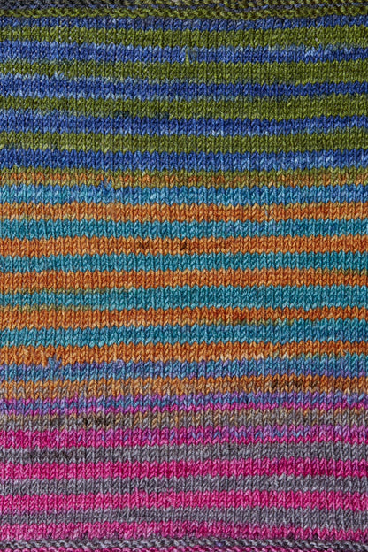 a knitted swatch of merino yarn with pink, green, orange, and teal tones from Urth yarns