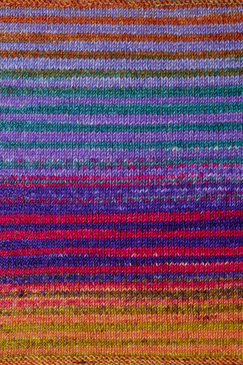 a knitted swatch of merino yarn with purple, teal, pink, and orange, and yellow tones from Urth yarns