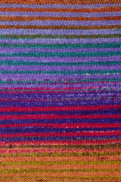 a knitted swatch of merino yarn with purple, teal, pink, and orange, and yellow tones from Urth yarns