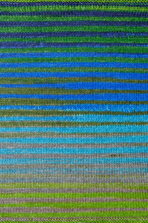 a knitted swatch of merino yarn with blue, green, grey tones from Urth yarns