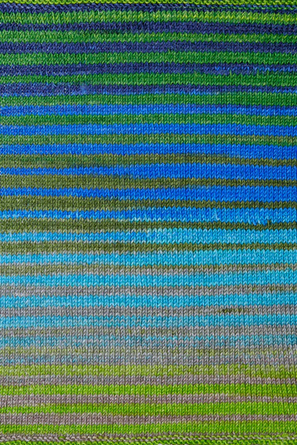 a knitted swatch of merino yarn with blue, green, grey tones from Urth yarns