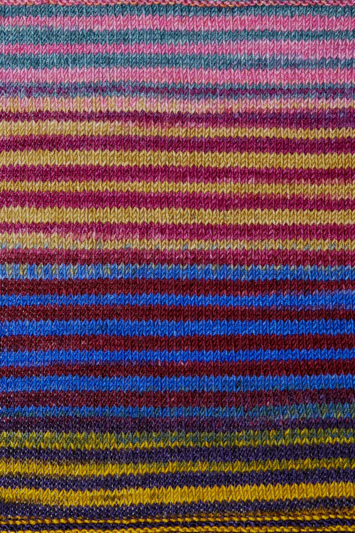 a knitted swatch of merino yarn with pink, marron, blue, purple, and yellow tones from Urth yarns