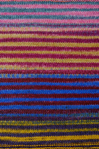 a knitted swatch of merino yarn with pink, marron, blue, purple, and yellow tones from Urth yarns