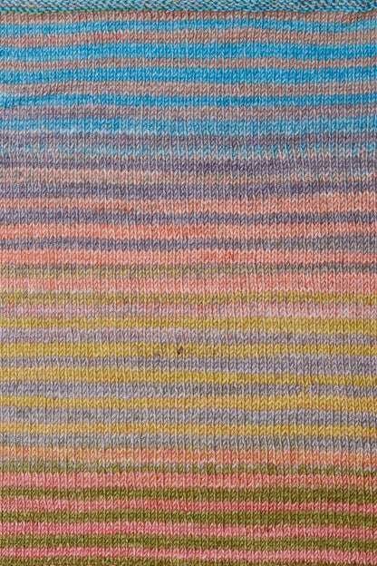 a knitted swatch of merino yarn with teal, grey, green, and peach tones from Urth yarns