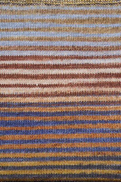 a knitted swatch of merino yarn with grey, brown, peach, orange, navy tones from Urth yarns
