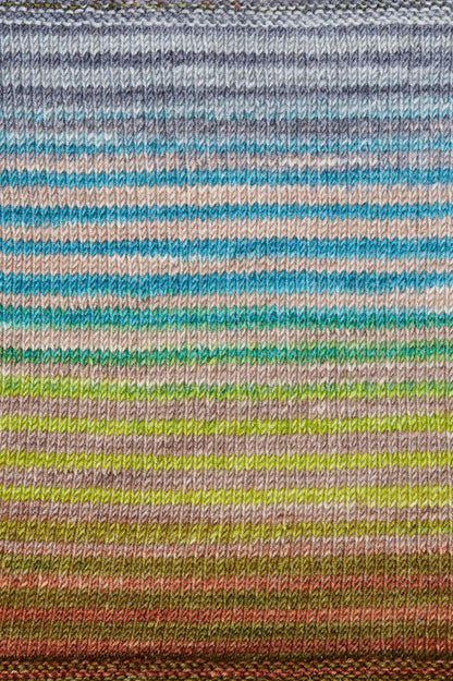 a knitted swatch of merino yarn with blue, grey, green, and grey tones from Urth yarns