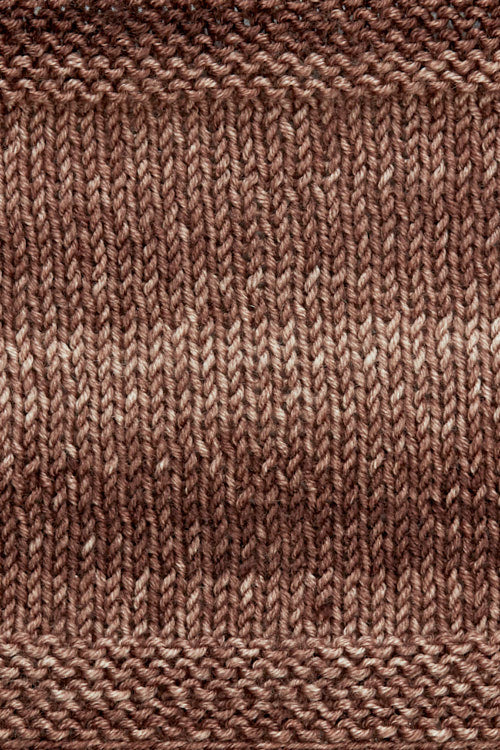 A knitted swatch of brown tonal superwash merino wool yarn from Urth