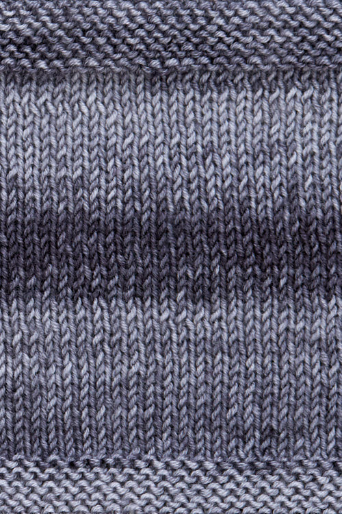 A knitted swatch of grey tonal superwash merino wool yarn from Urth