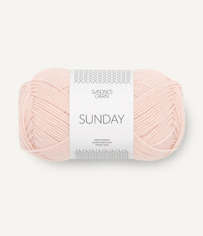 A ball of Sandnesgarn Sunday merino wool yarn in a blush color, with packaging that includes the brand and product name.
