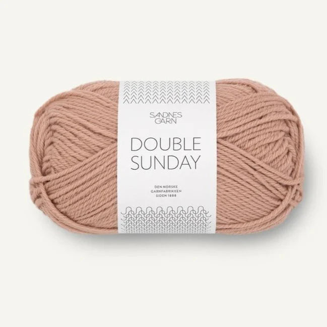 A ball of peach coloured merino wool yarn labeled 'Double Sunday' by Sandnesgarn.