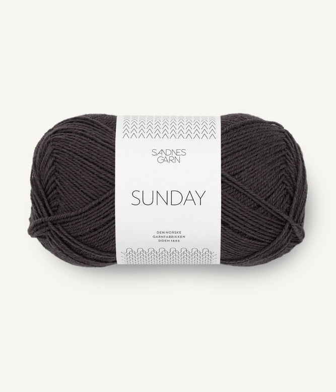 A ball of Sandnesgarn Sunday merino wool yarn in a brown-black color, with packaging that includes the brand and product name.