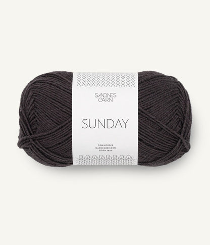 A ball of Sandnesgarn Sunday merino wool yarn in a brown-black color, with packaging that includes the brand and product name.
