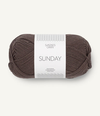 A ball of Sandnesgarn Sunday merino wool yarn in a dark brown color, with packaging that includes the brand and product name.