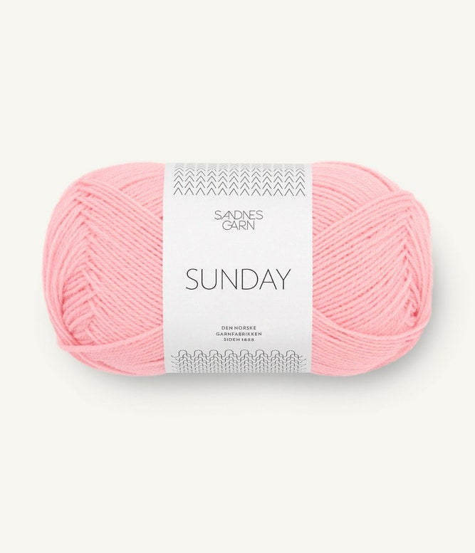 A ball of Sandnesgarn Sunday merino wool yarn in a light pink color, with packaging that includes the brand and product name.