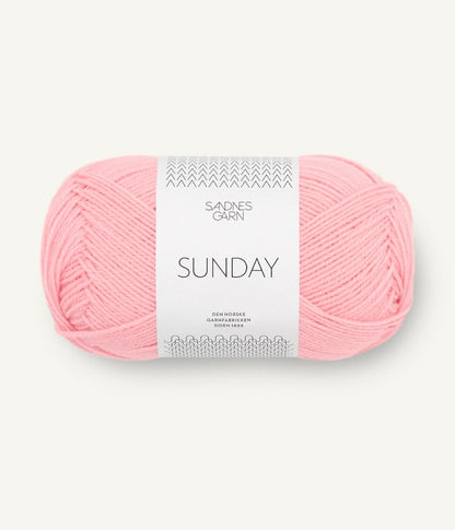 A ball of Sandnesgarn Sunday merino wool yarn in a light pink color, with packaging that includes the brand and product name.